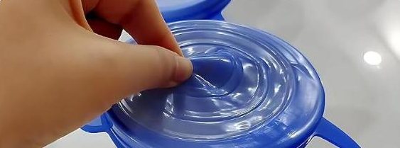 Fingers pressing the centre of a blue lid